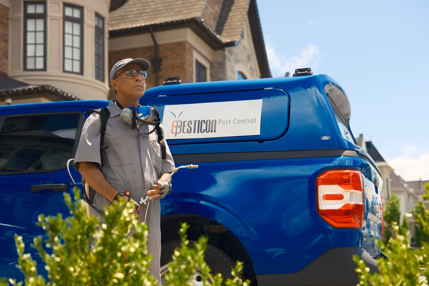 Pesticon pest control technician with a backpack sprayer beside a branded blue Pesticon service truck outside a Markham home